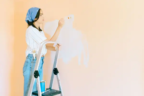 Interior painting in Peoria: painter on a stepladder rolling a wall